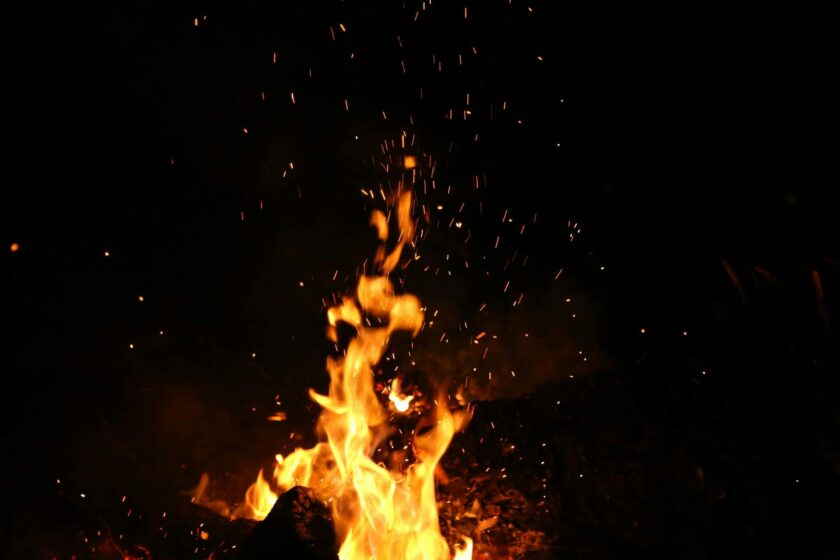 Mesmerizing campfire flames and sparks against a dark nighttime backdrop.